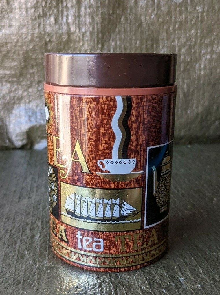 TEA CADDY TIN, GOLD, BLACK, BROWN AND WHITE GRAPHICS. 4 1/2 INCHES TALL.