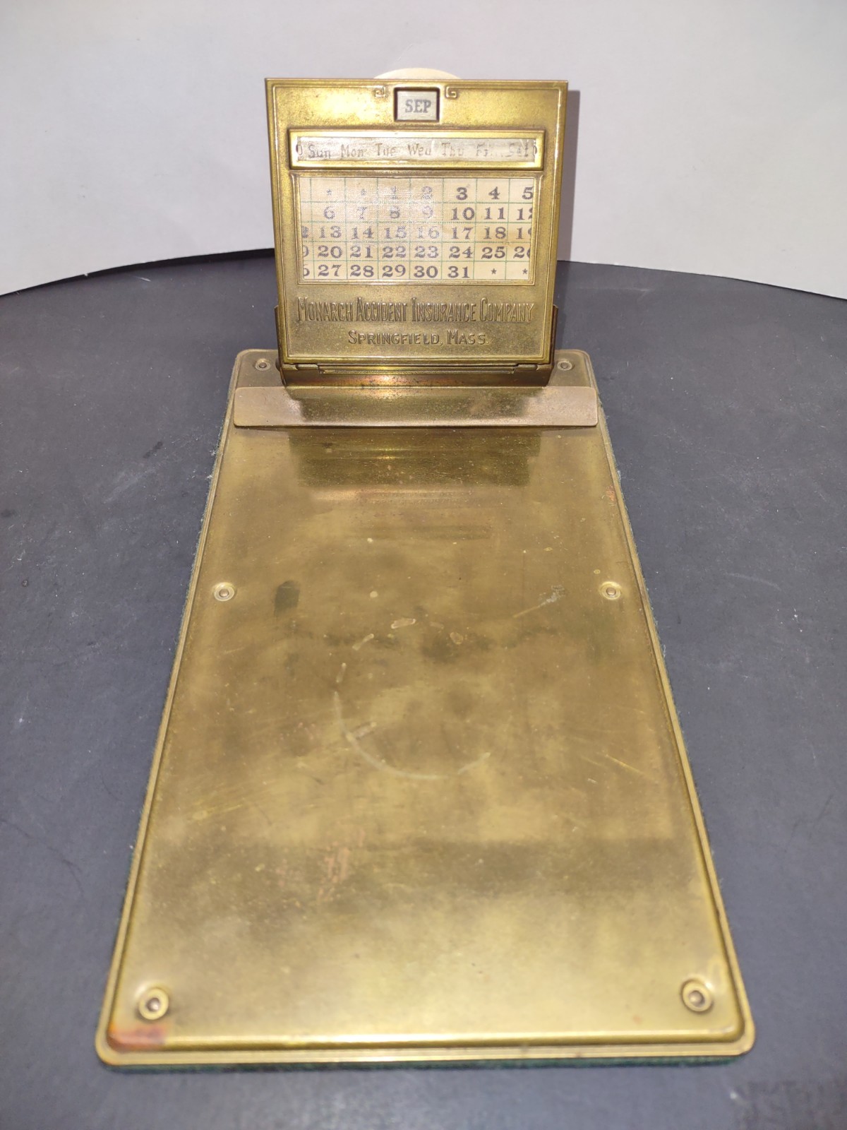 J E Mergott BRASS ADVERTISING CLIPBOARD CALENDAR MONARCH ACCIDENT INSURANCE Comp